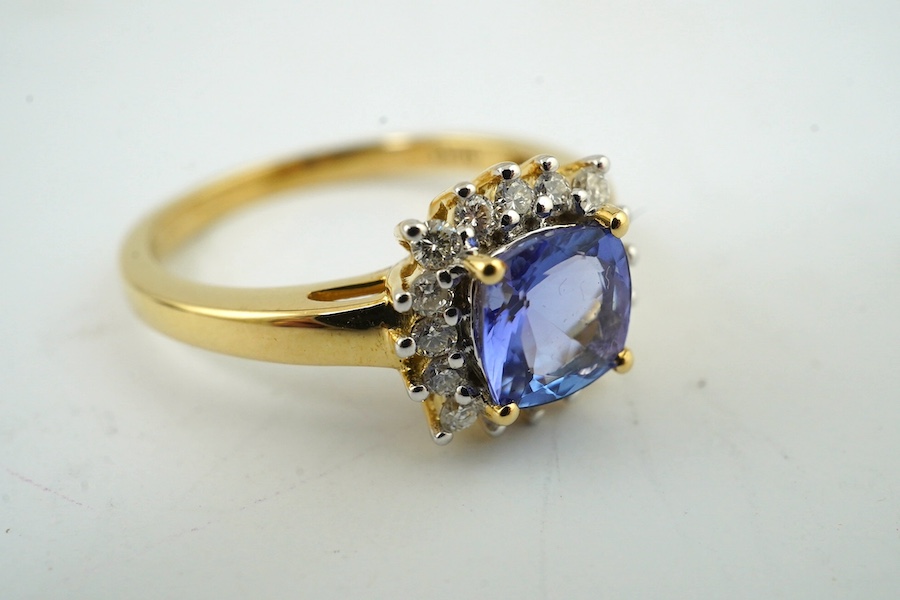 A modern 18ct gold, tanzanite and diamond cluster set ring, with AnchorCert report estimating the cushion cut tanzanite to weigh 0.90ct, size O, gross weight 3.5 grams. Condition - good